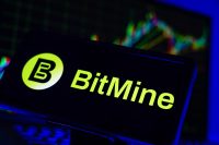 A smartphone displays the logo for BitMine, a digital asset company. In the background, a financial chart is visible, representing the market volatility referenced in the October 2025 article about BitMine's large Ether acquisition post-crash.