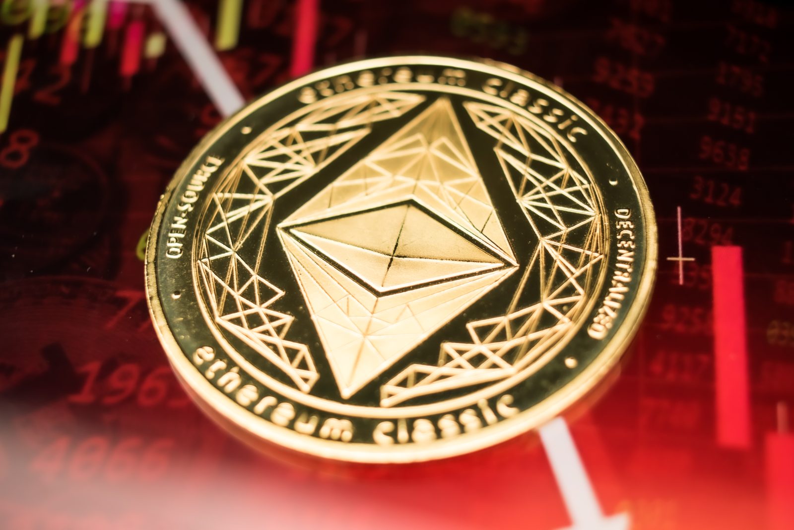A physical, gold-colored Ethereum Classic (ETC) coin is shown against a red, bearish financial chart with downward-trending lines and data. The image represents the broader cryptocurrency market's downturn, setting the context for an October 2025 article where Ethereum (ETH) showed relative strength compared to other altcoins during a 'Black Monday' event.