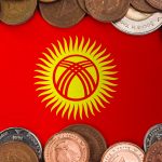 The flag of Kyrgyzstan is framed by a border of various international coins. This image represents the nation's financial system and currency (the Som), relevant to the October 2025 article about Kyrgyzstan launching a Som-pegged stablecoin and accelerating its Central Bank Digital Currency (CBDC) pilot.