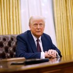 President Donald Trump sits at the Resolute Desk in the Oval Office.