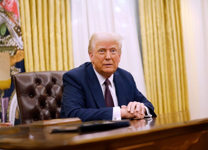 President Donald Trump sits at the Resolute Desk in the Oval Office.