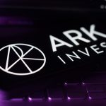 A smartphone displaying the logo for ARK Invest, resting on a keyboard.