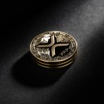 A physical Ripple (XRP) coin is shown in a dramatic spotlight on a dark background.