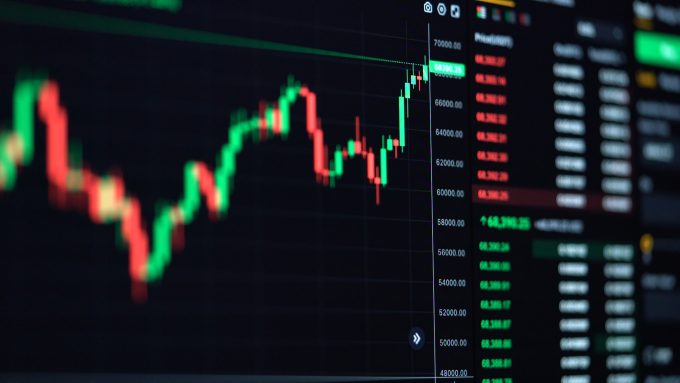 A close-up of a digital cryptocurrency trading chart displaying red and green candlesticks against a dark background.