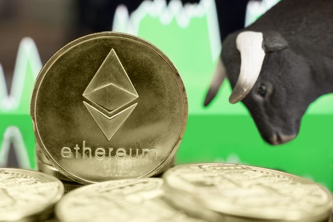 A gold physical Ethereum coin standing in the foreground, backed by a rising green market chart and a bull figurine, symbolizing a bullish trend.