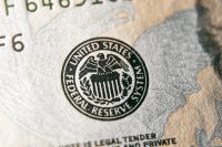 A macro close-up of the Federal Reserve System seal on a US dollar bill, focusing on the eagle emblem.