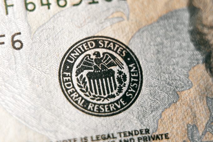 A macro close-up of the Federal Reserve System seal on a US dollar bill, focusing on the eagle emblem.
