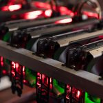 A close-up view of a cryptocurrency mining rig with multiple graphics cards (GPUs) illuminated by red LED lights.