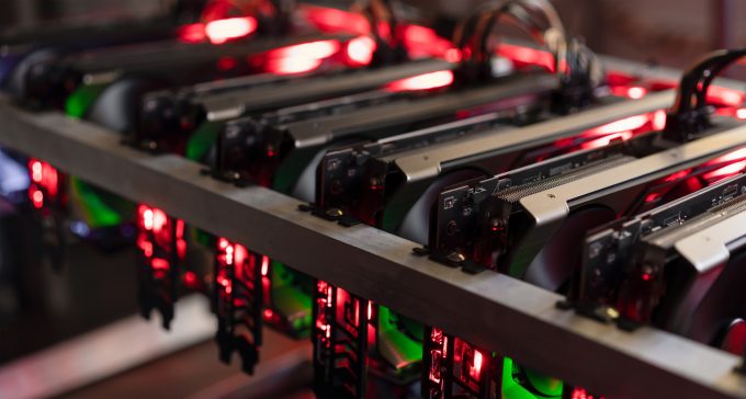 A close-up view of a cryptocurrency mining rig with multiple graphics cards (GPUs) illuminated by red LED lights.